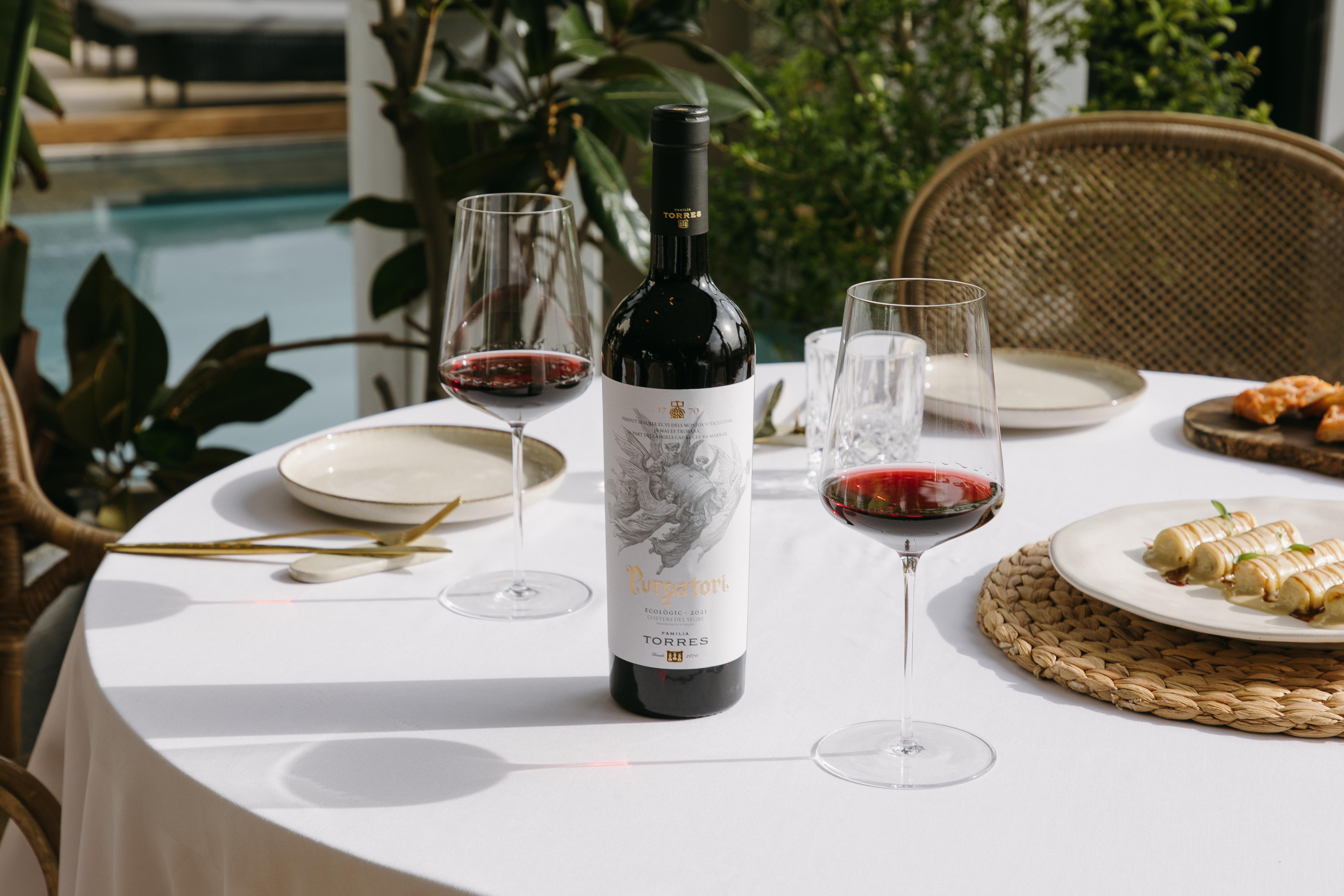 Comida en una terraza acompañada del vino tinto Purgatori, con copas de cristal.  