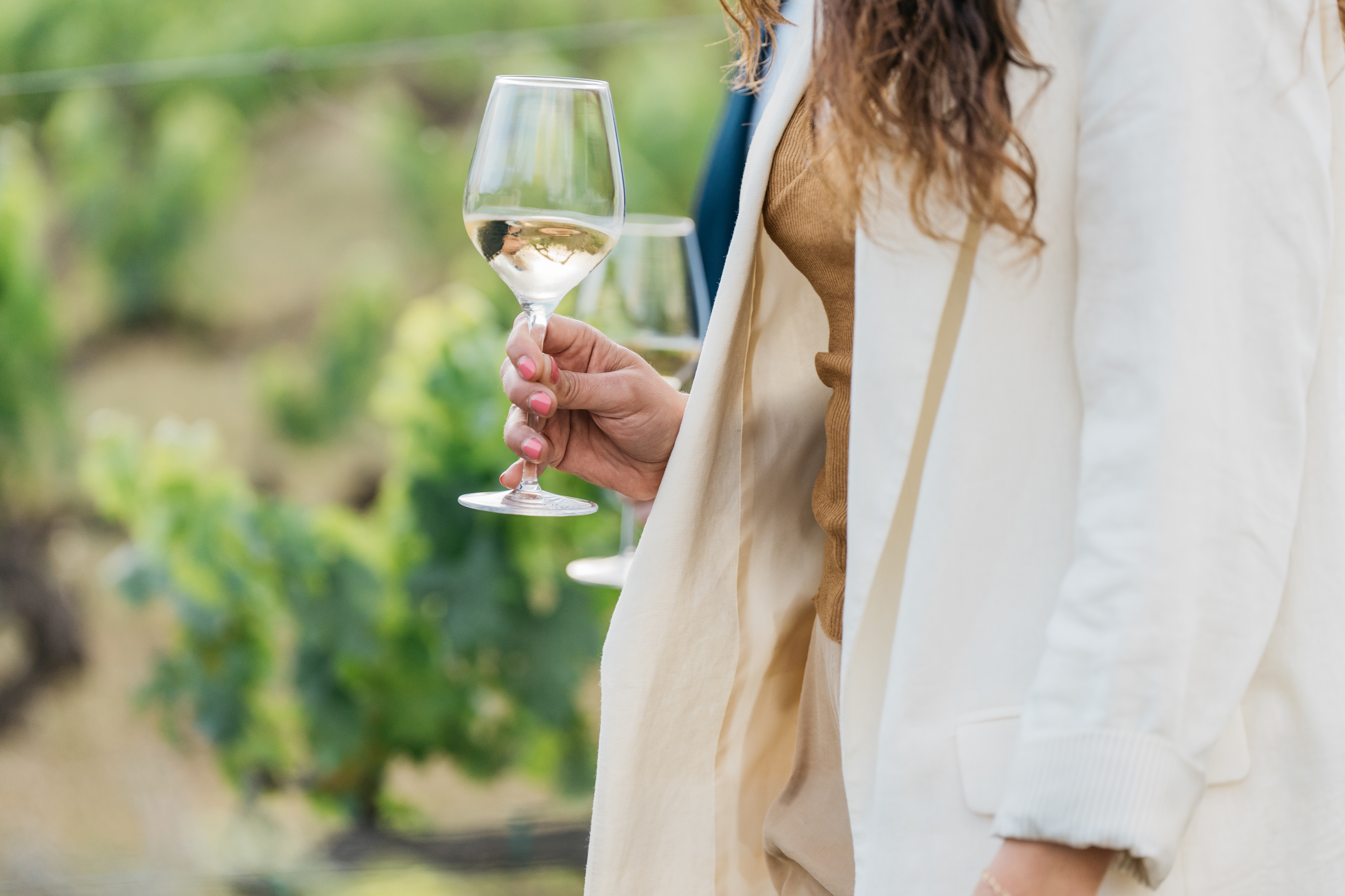 Persona disfrutando de una copa de vino en los viñedos de Familia Torres 