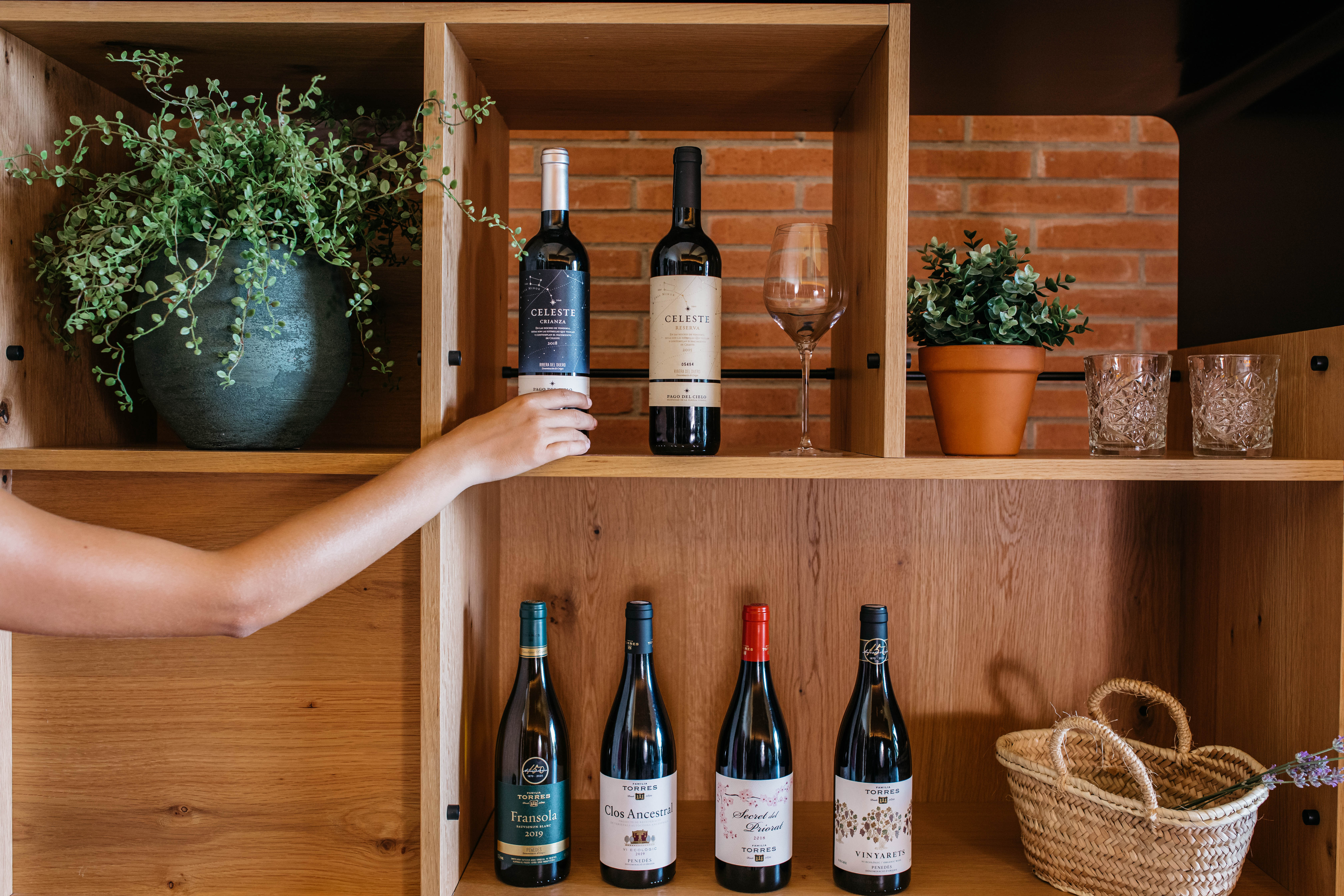 Una estantería de madera con una selección de vinos en un hogar, creando un ambiente rústico y acogedor.