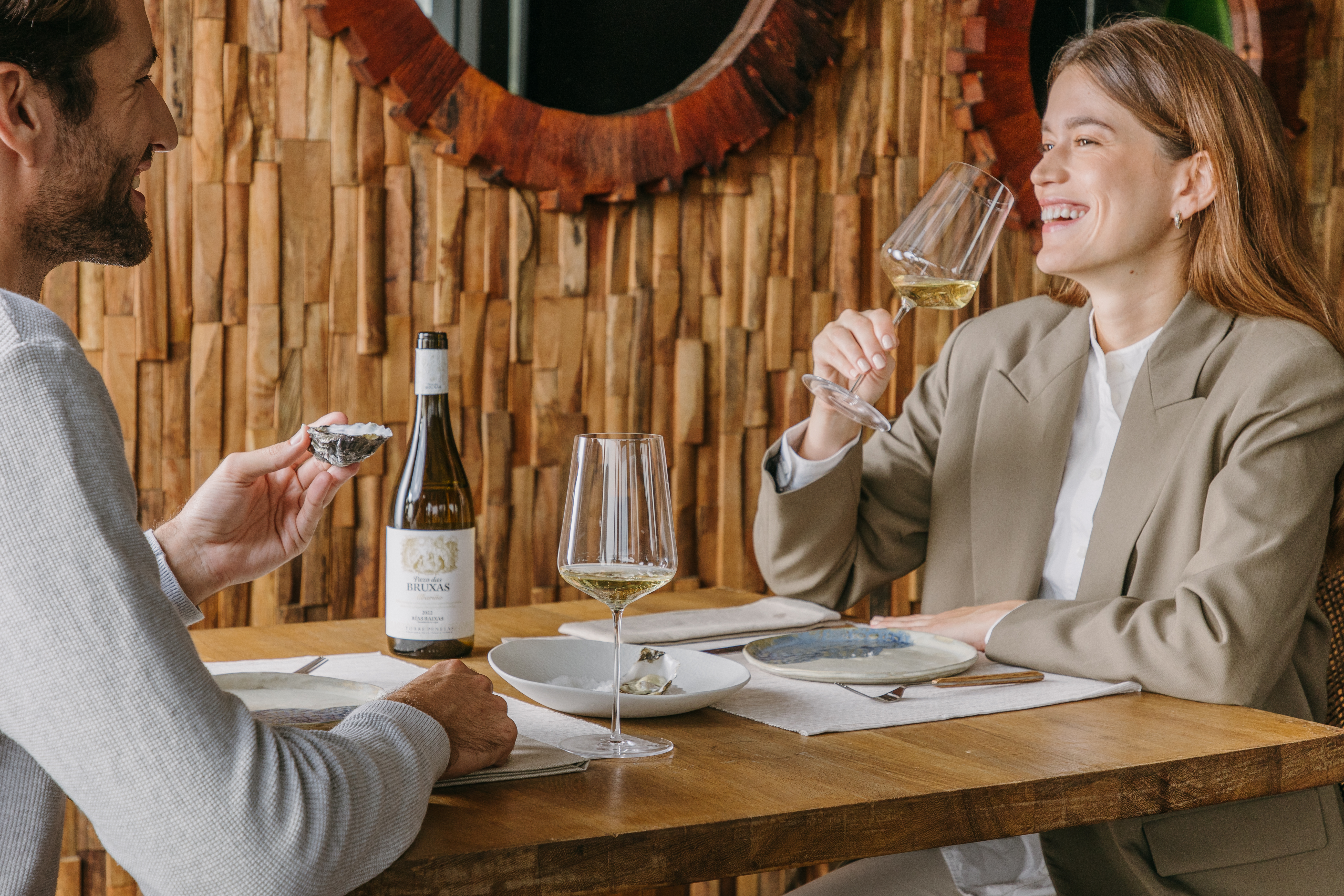 Una pareja disfrutando de una comida maridada con el vino Pazo das Bruxas, propiedad de Familia Torres.