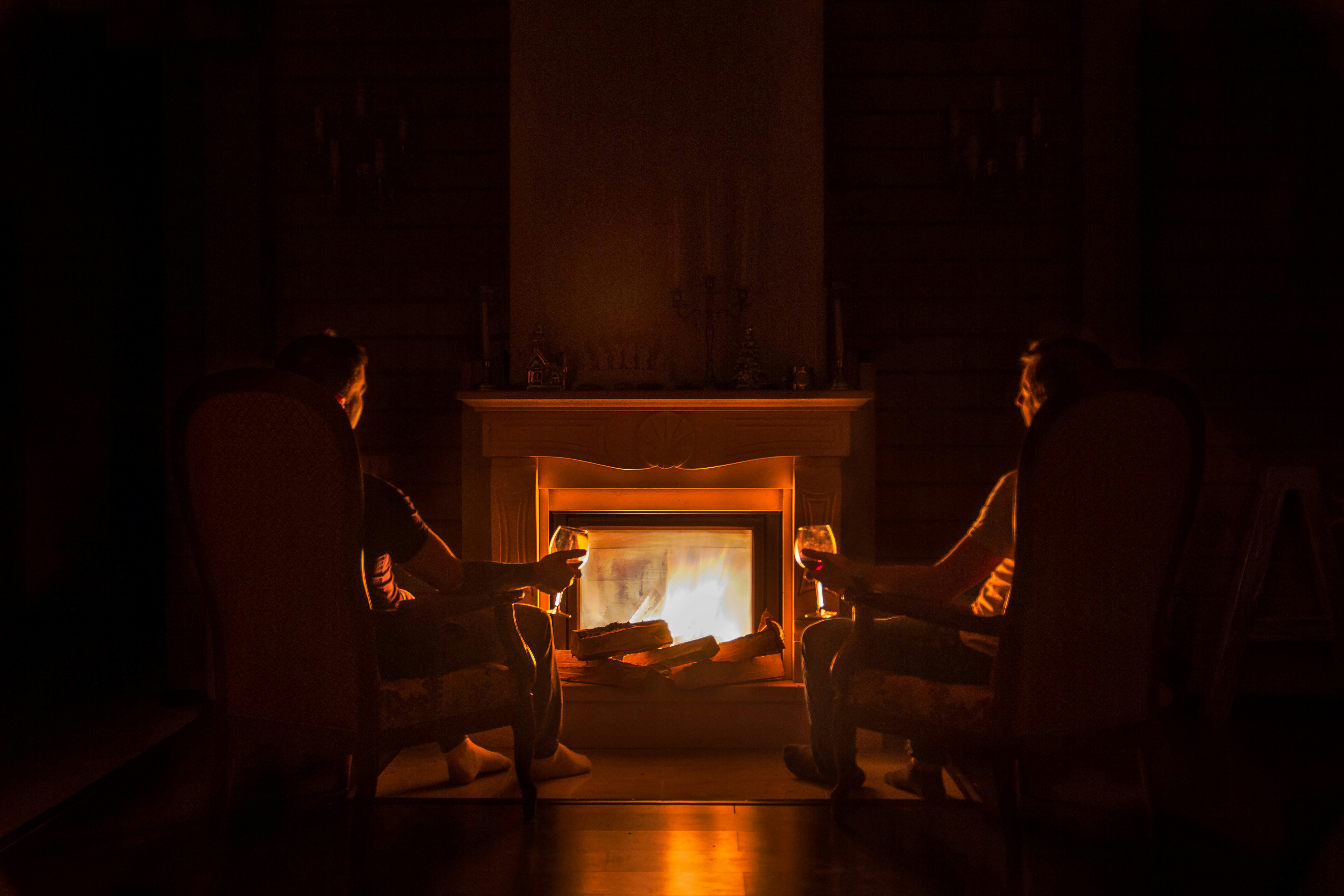Dos personas delante de la chimenea degustando una copa de vino.