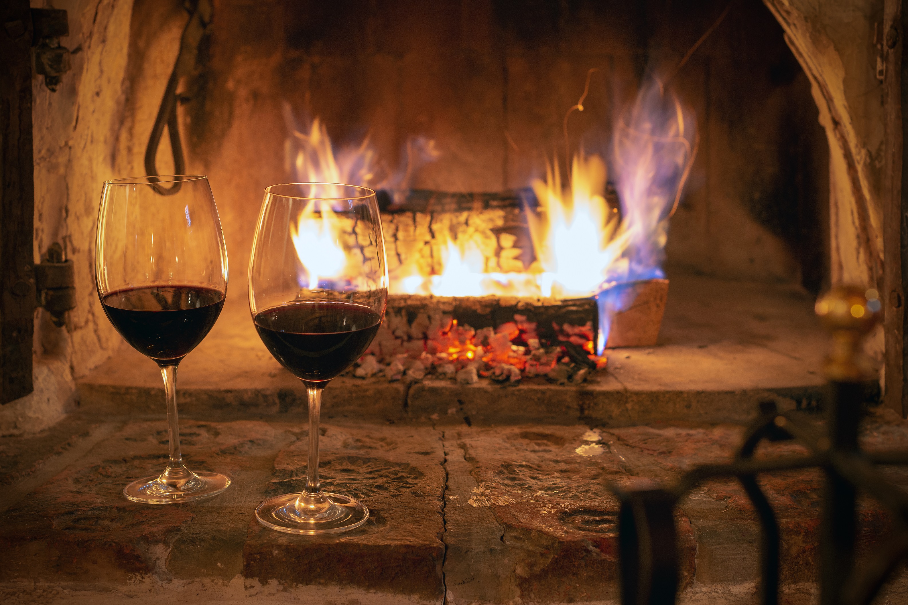 TINTOS CÁLIDOS PARA FRÍOS DÍAS DE INVIERNO Dos copas de vino tinto delante del fuego. Una escena perfecta para un día de temperaturas invernales.